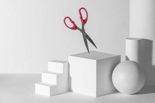 Scissors with pink handles among white 3d paper shapes