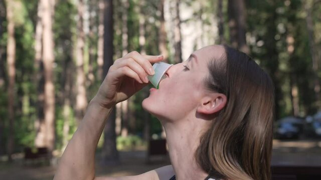 This video shows a side, profile view of a camper caucasian woman eating a jello shot in the forest.