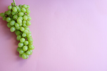 a bunch of green grapes on a pink background
