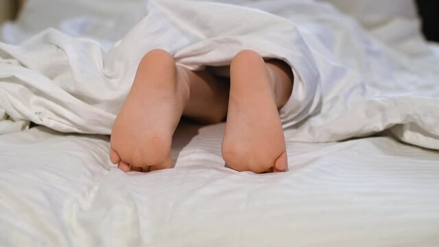 Child feet peeking out from under the blanket. Morning concept.