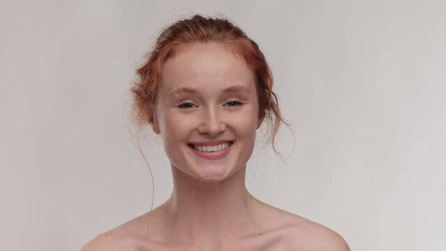 Close up portrait young beautiful ginger girl. Beauty and skin care. Adorable young half-naked woman look at the camera and smiling. Advertising fresh clean healthy skin care concept. Slow motion.