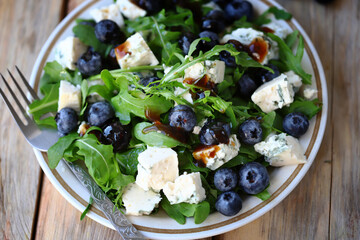 Healthy tasty salad with arugula, blue cheese and blueberries. Keto salad. Summer health food.