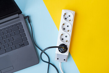 A laptop being charged on yellow and blue background