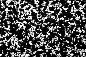 A wall, a floor consisting of many small stones of black and white colors. A wall with cracks