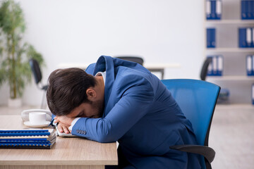 Obraz premium Young male employee unhappy with excessive work in the office