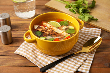 Bowl of tasty Sopa de Lima soup on wooden background