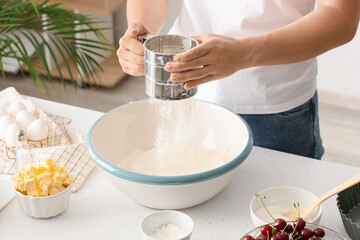 Woman preparing dough for cherry pie at table