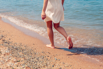 Woman walking on sand beach closeup. Beach travel. Woman walking on beach leaving footprints in the sand