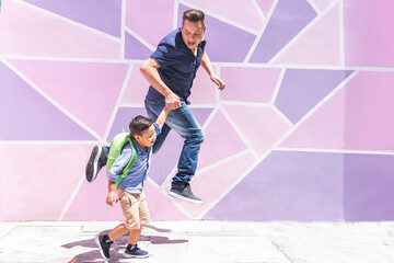 Father and son jumping and running to school on a purple and pink urban background. Back to school