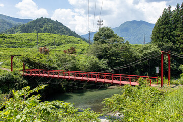 山間を流れる川に架けられた鉄製の赤い吊り橋