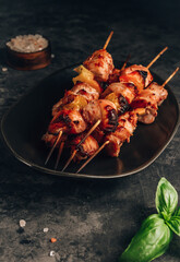 Grilled meat skewers. Chicken shashlik and vegetables on dark background. Selective focus