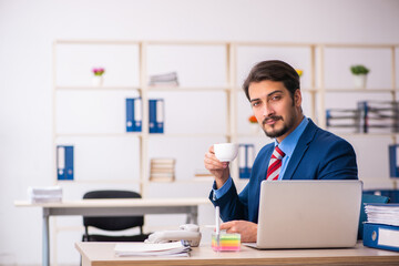 Fototapeta premium Young male employee drinking coffee during break