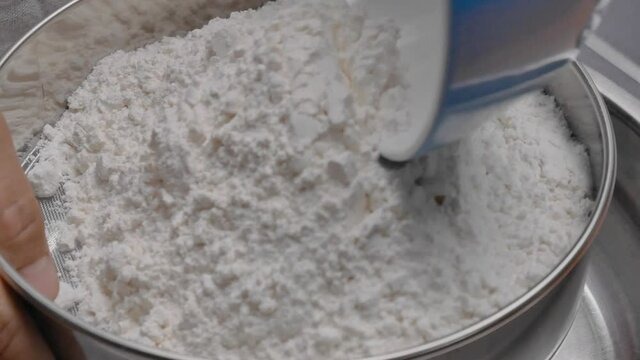 Female hands mixing flour and eggs with a ladle prepared for homemade pizza dough or bread. Cooking process.