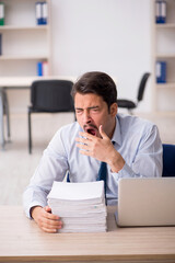 Naklejka premium Young male employee unhappy with excessive work in the office