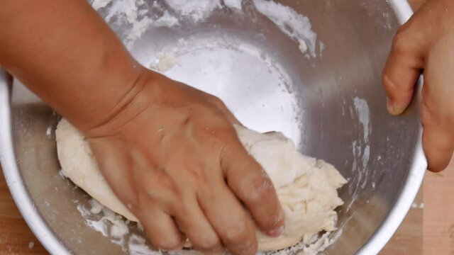 Female hands mixing flour, fresh milk and chicken eggs prepares dough for homemade pizza. Cooking process.
