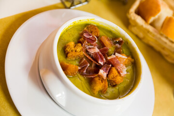 Zucchini cream soup with crispy croutons and dry cured ham shavings. Spanish cuisine..