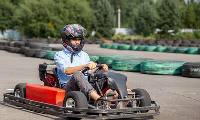 Naklejka premium A girl or a woman in a helmet rides a go-kart on a special track.