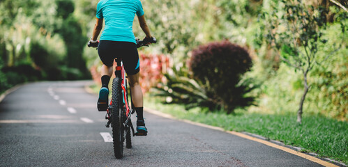 Woman cycling on tropical park trail in summer