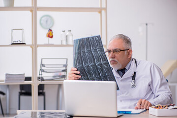 Old male doctor radiologist working in the clinic