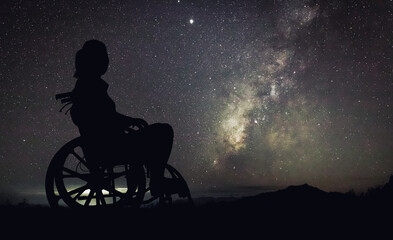 Silhouette Disabled handicapped woman is sitting on wheelchair looking Night landscape with...