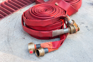 Red fire hose laid on concrete floor. Firefighters prepare to extinguish the fire.