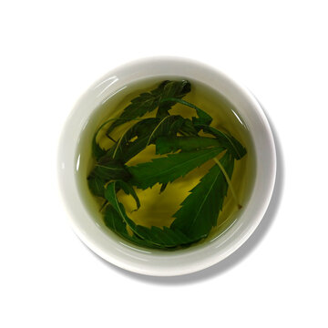 Herbal tea, cannabis leaf tea in a ceramic mug on white background.