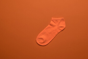 Bright orange sock on an orange background. Flat lay.