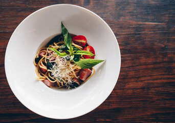 Spaghetti with chili paste and ham served in white dish on wooden table. Spaghetti is one of the most popular forms of pasta, and it's used in dishes all around the world, is fairly neutral, diet.