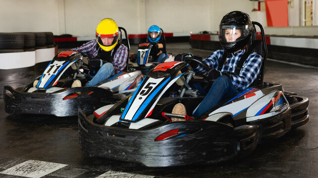 Young active people driving sport cars for karting in a circuit lap in sport club