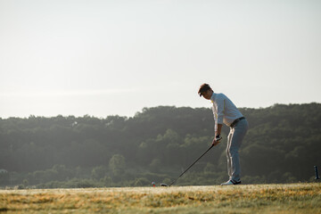 Golfers in a ready position plays swing shot on teeing ground in warm sunshine. leisure and sport...