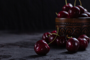 Organic juicy cherry in a bowl on dark background. Close-up photo, low key, selective focus