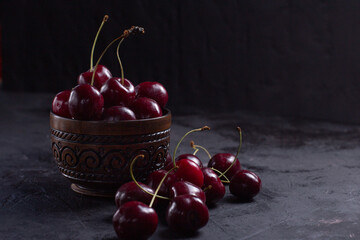 Organic juicy cherry in a bowl on dark background. Close-up photo, low key