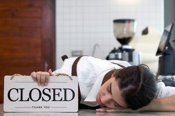 Young caucasian shopkeeper fell asleep on a coffee shop counter while holding a 