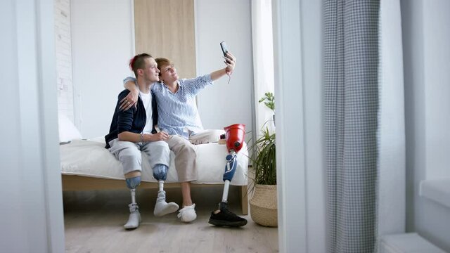Disabled people taking selfie on bed indoors at home, leg amputee and prosthetic concept.