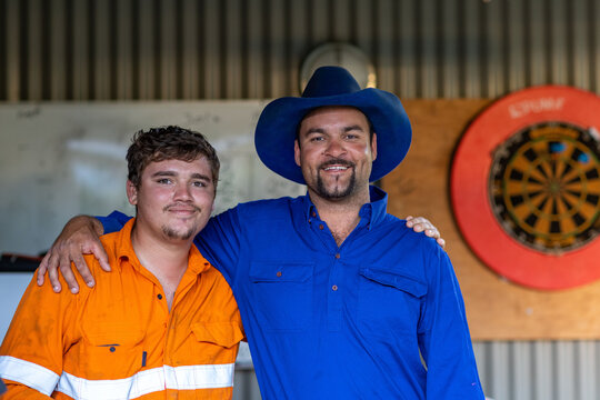 man with arm around shoulder of younger man in tradie shirt