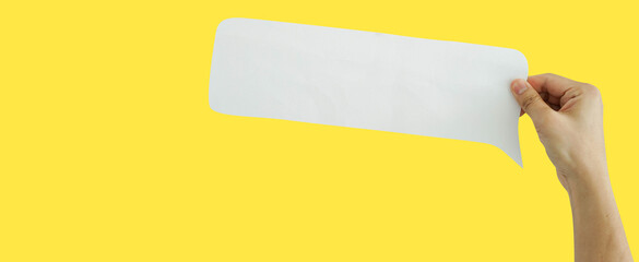 close up man hand hold speech bubble paper cut isolated n yellow background for design concept