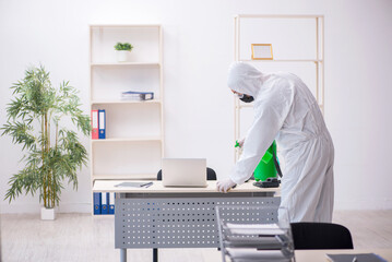 Young male contractor disinfecting office during pandemic