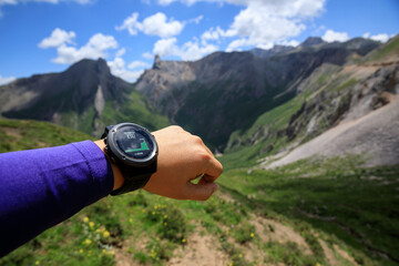 Hiker on high altitude mountain top checking the altimeter on the sports watch