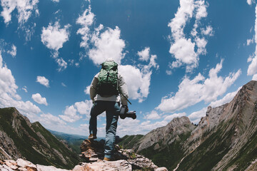 Woman hiker with camera on high altitude mountain top