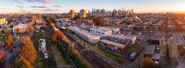 Aerial panoramic view of a busy city suburb at sunset with a railway line running through it