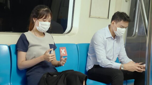 Asian working women wear face mask to prevent COVID-19 while traveling in transport subway. Spray alcohol to clean hands. Caution in coronavirus epidemic situation travel to work. social distancing  