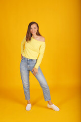 Fototapeta premium a young beautiful blonde girl in a yellow jacket and jeans holds a pose in full-length movement
