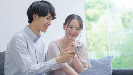 スマホを見る若い夫婦・カップル