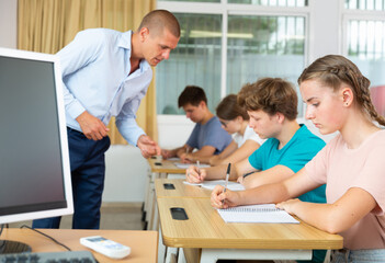 Fototapeta premium Teenagers listening to lecturer and writing in notebooks. High quality photo