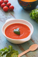 Tomato soup with basil on blue background
