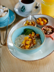 Bowl with oatmeal and diet fruits, berries, nuts and honey. Home heathy breakfast food concept with natural sun light