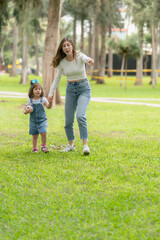 Fototapeta premium Mother holding the hand of a girl with a ball in a park