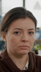 Close up of business woman with disabilities looking sad at camera while diverse team working at financial project. Multiethnic coworkers talking in startup financial company with modern workspace