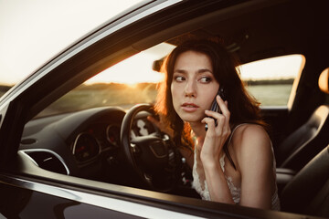 Fototapeta na wymiar Portrait of woman talking on mobile phone while driving her car