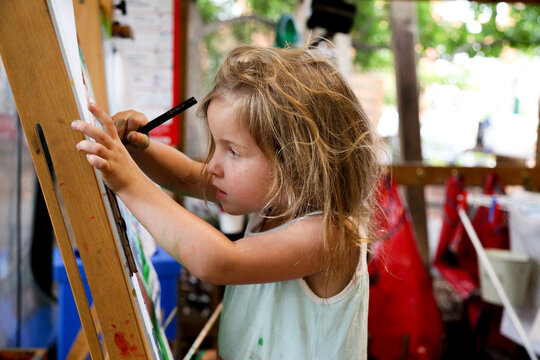 Young girl drawing using an easel at preschool